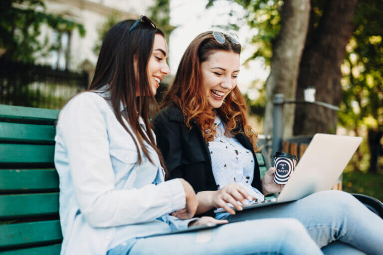 Two actresses on a park bench looking into all the activities they can do this month.