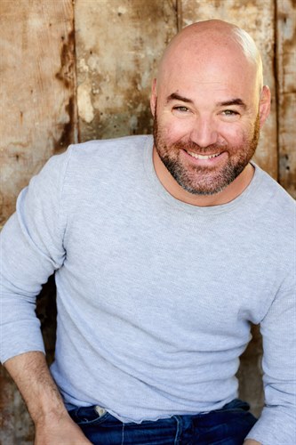 Orion McCabe smiling outside in a gray sweater.