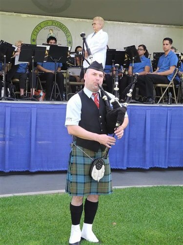 Orion McCabe in uniform on a field playing the bagpipes.