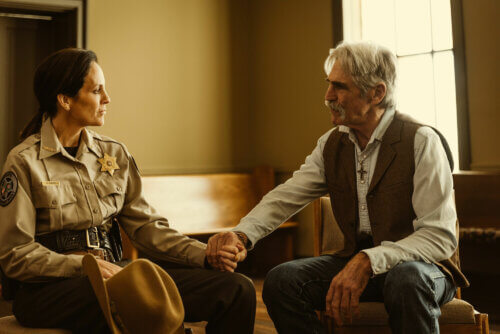 Annabeth Gish and Forrie J. Smith as a cowboy and sheriff talking inside.