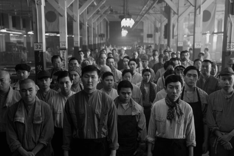 Black and white still of Japanese factory workers in Nagasaki.