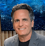 Darren Anselmo sitting in a restaurant smiling in front of a fish tank.