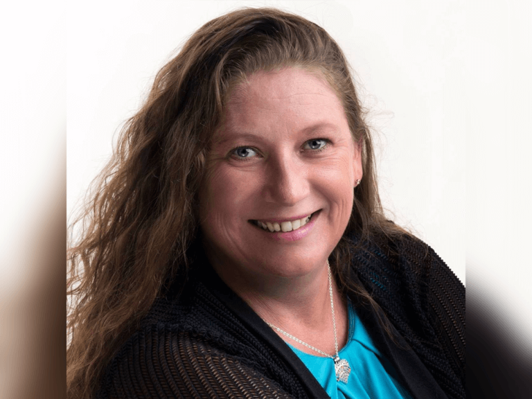 Casting director Nancy McBride smiling in a blue shirt and black cardigan.