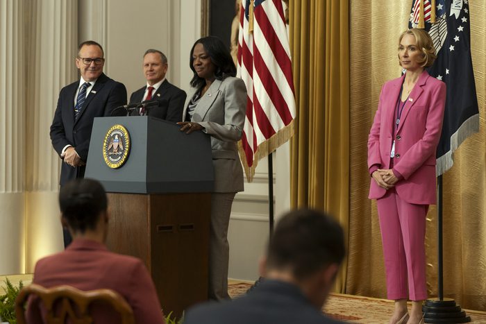 Clark Gregg and Elizabeth Marvel watching Viola Davis, give a presidential speech behind a podium in the movie G20.